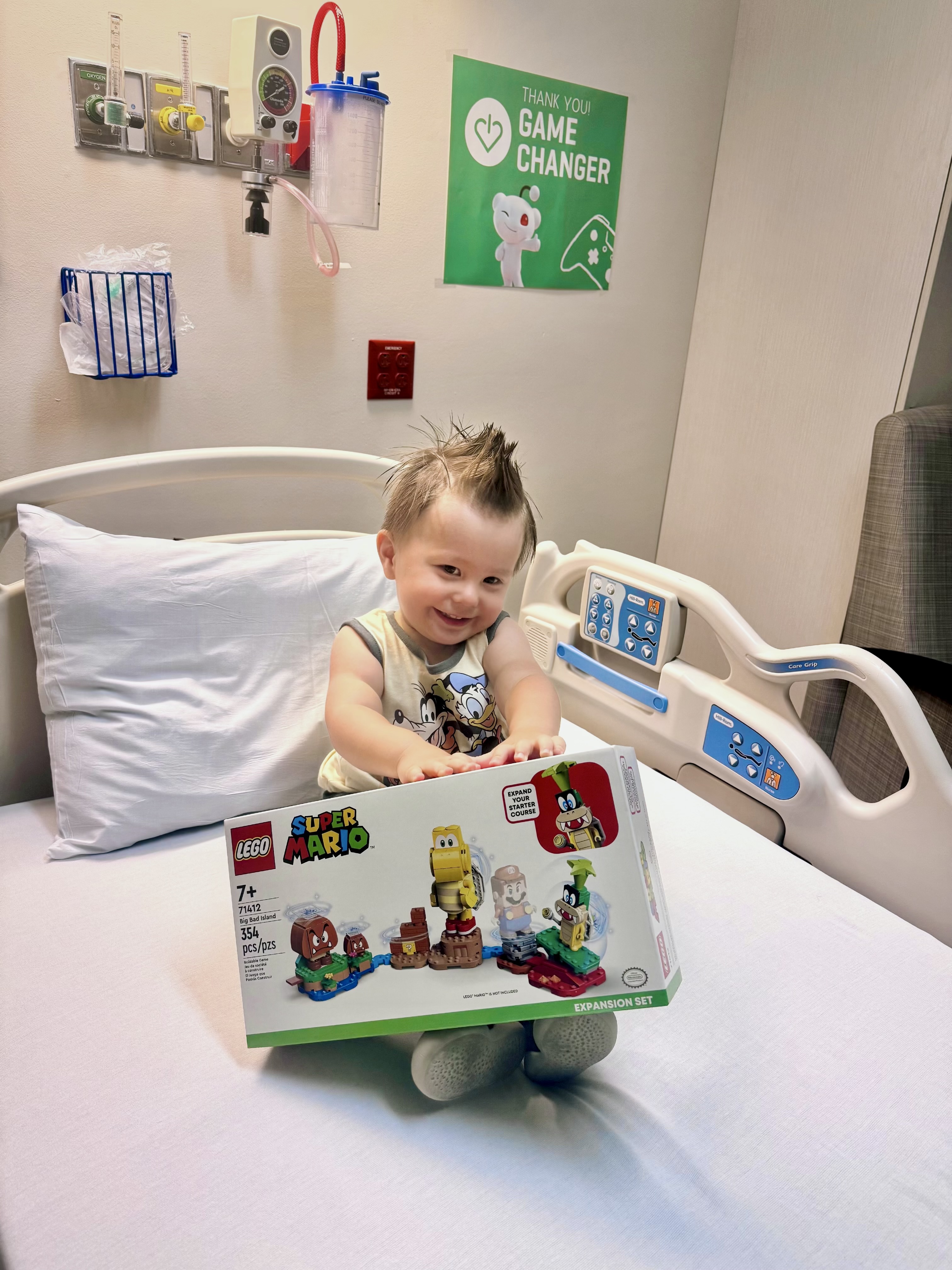 A smiling toddler in the hospital with a new LEGO set.